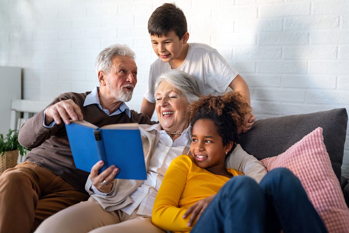 Grandparents and grandchildren reading a book on a couch
