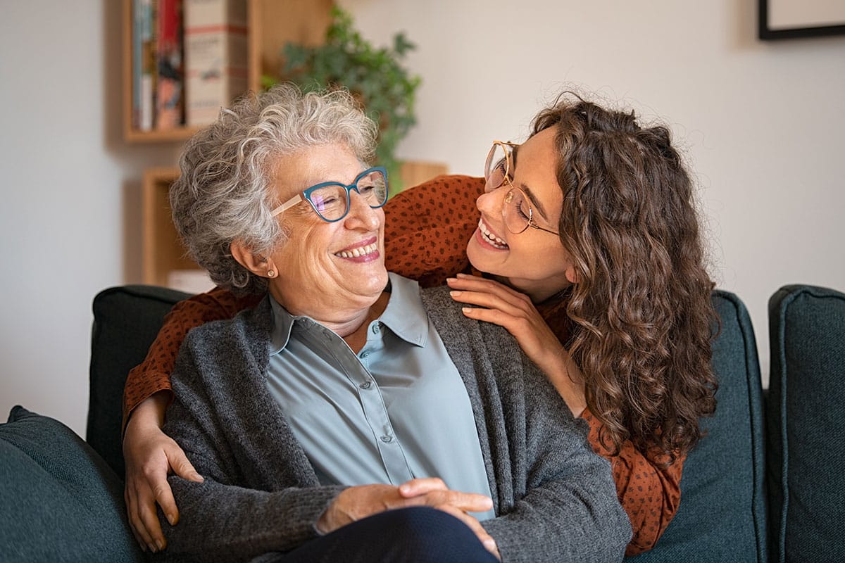 Two women smiling on couch-
