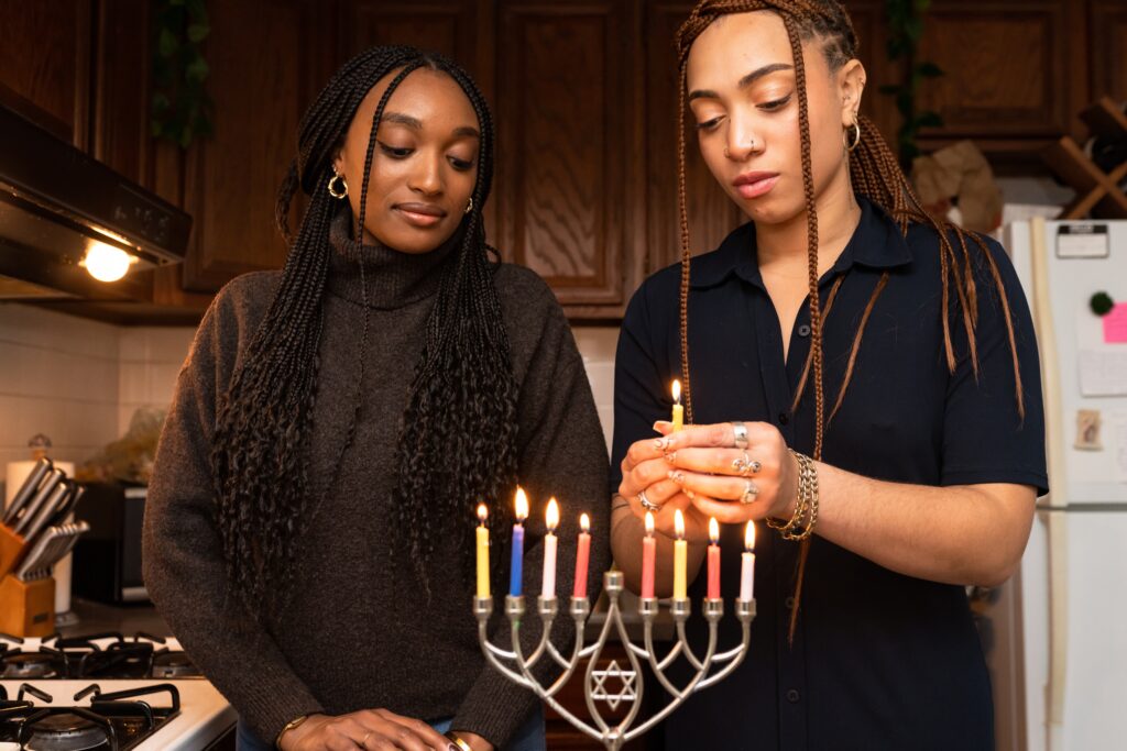 Two Black Jewish women light a menorah