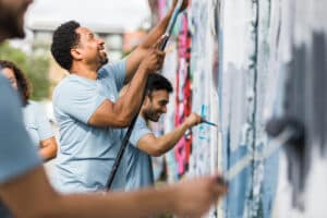 Nonprofit staff and volunteers smiling while they paint